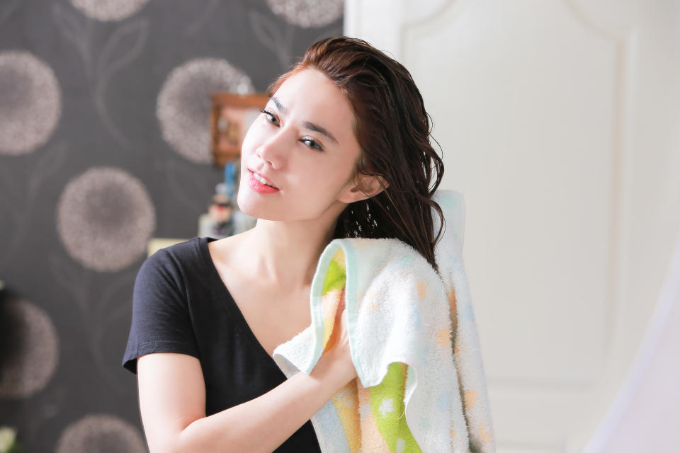 Hair slugging young asian woman using a towel on wet hair