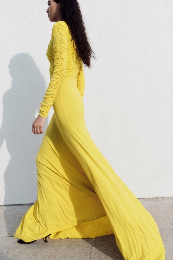 A model, shot from the side, wearing a canary yellow gown