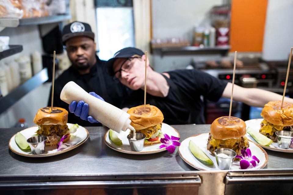 Line cook Zach Harrow, center, prepares a course as fellow line cook Dequan Marvin watches during a Detroit Free Press Top 10 Takeover dinner at Mudgie's in Detroit on Wednesday, July 6, 2022.