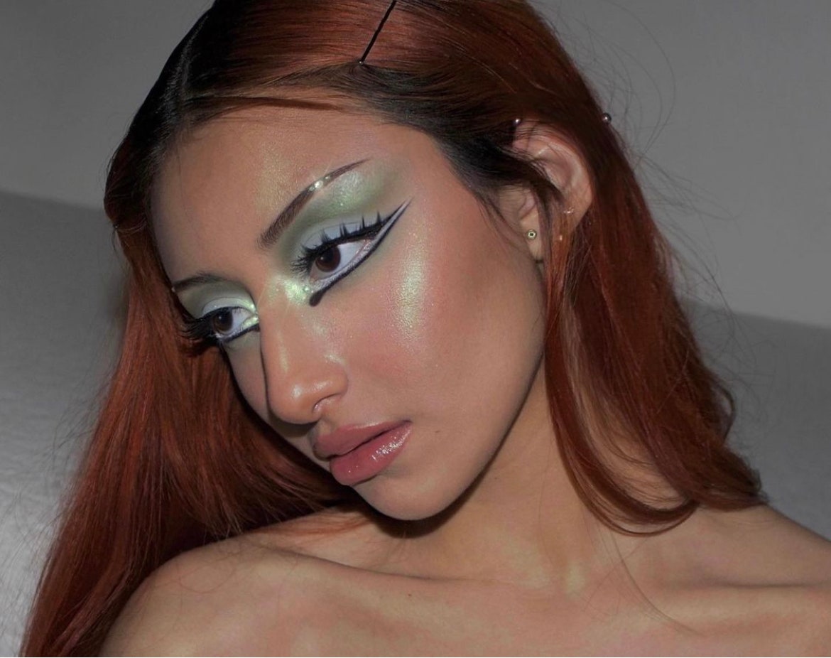 A woman wearing green eyeshadow on her eyes and cheekbones